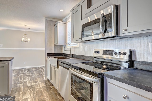kitchen featuring a sink, appliances with stainless steel finishes, wood finished floors, and dark countertops