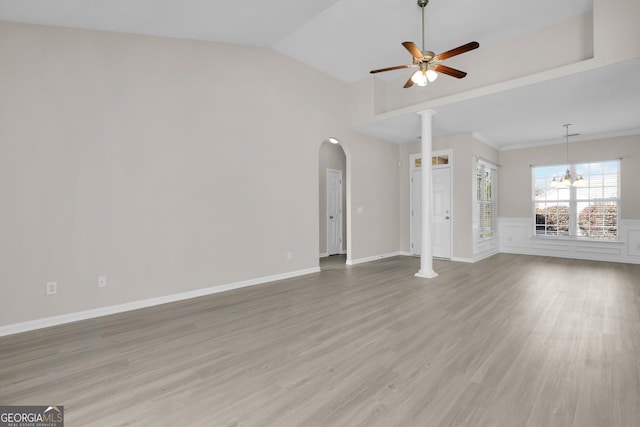 unfurnished living room with arched walkways, ceiling fan with notable chandelier, decorative columns, lofted ceiling, and light wood-type flooring