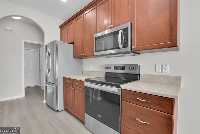 kitchen with light countertops, appliances with stainless steel finishes, brown cabinets, and light wood finished floors