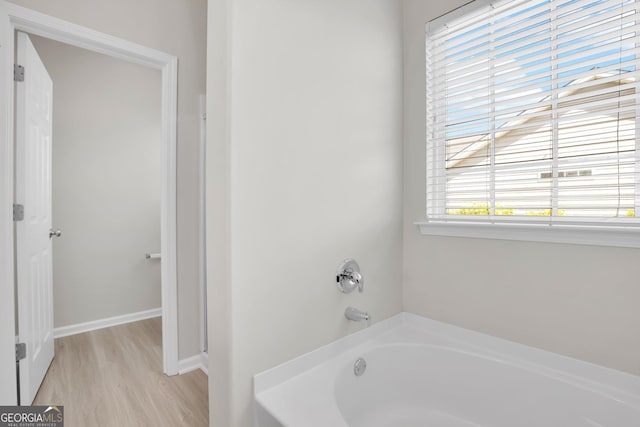 full bath featuring baseboards, wood finished floors, and a bath