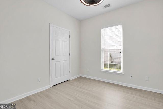 spare room featuring light wood-type flooring, baseboards, and visible vents