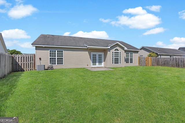 rear view of house with a lawn, french doors, a fenced backyard, and central AC unit