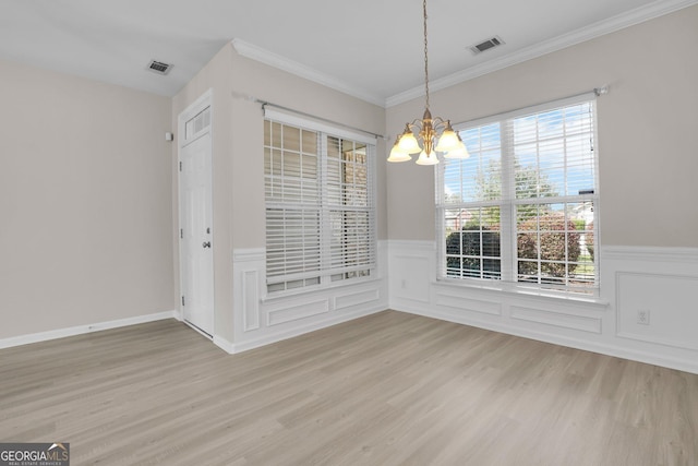 unfurnished dining area featuring a chandelier, visible vents, light wood-style flooring, and a wainscoted wall