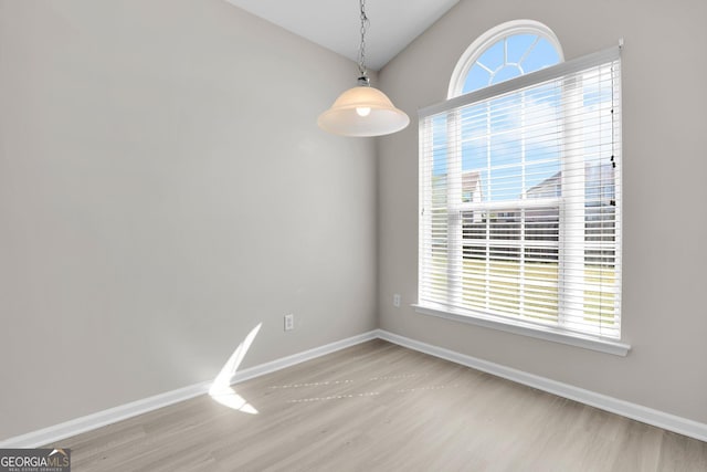 unfurnished dining area featuring baseboards, light wood finished floors, and lofted ceiling