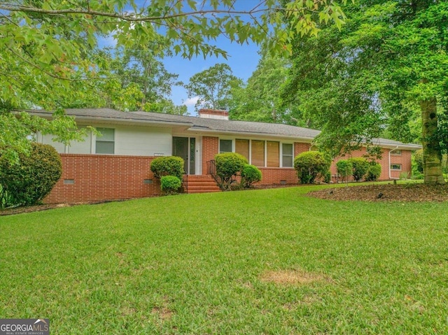 ranch-style home with a chimney, a front yard, crawl space, and brick siding