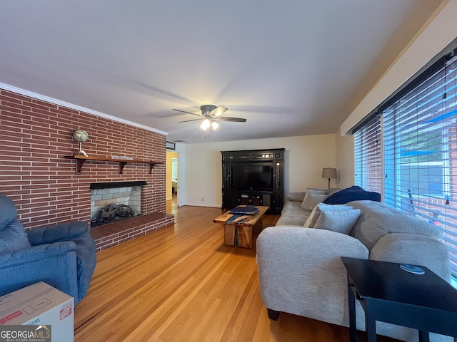 living area with a ceiling fan, wood finished floors, and a fireplace