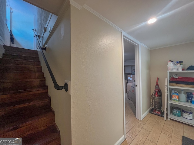 stairway featuring crown molding, baseboards, and wood finished floors