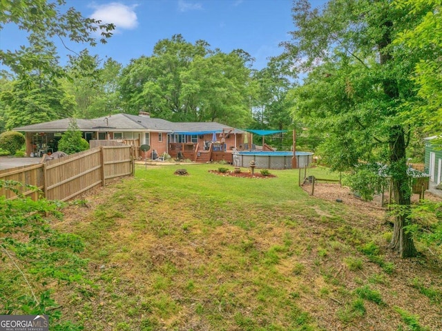 view of yard with fence, a deck, and an outdoor pool
