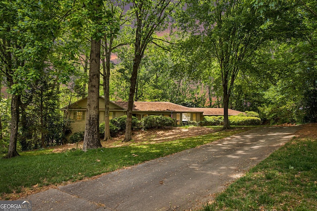 ranch-style house featuring a front lawn and aphalt driveway