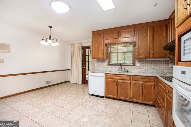 kitchen featuring decorative backsplash, brown cabinetry, visible vents, a sink, and white appliances