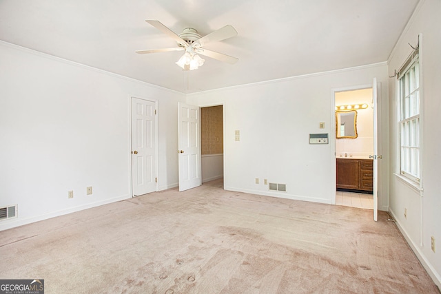 unfurnished bedroom with visible vents, light colored carpet, baseboards, connected bathroom, and ornamental molding