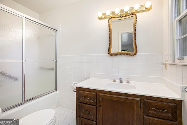 bathroom with tile walls, a wainscoted wall, vanity, toilet, and enclosed tub / shower combo