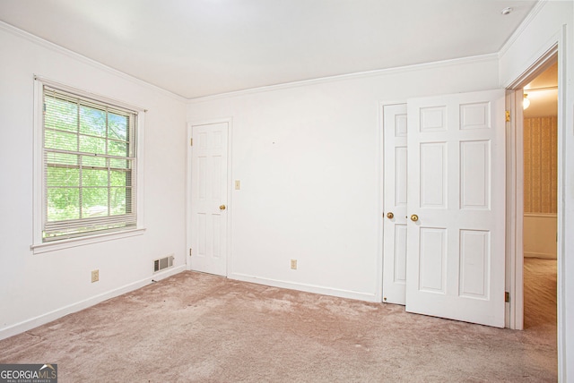 carpeted empty room with crown molding, baseboards, and visible vents