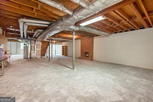 basement featuring water heater, a brick fireplace, and stairs