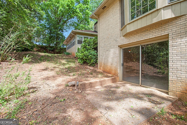 view of side of home featuring brick siding and a patio area