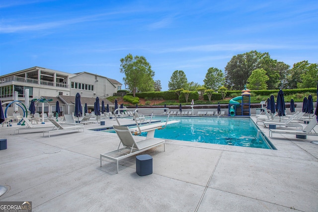 community pool with a water slide and a patio area