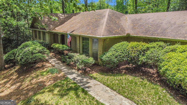ranch-style home with roof with shingles and brick siding