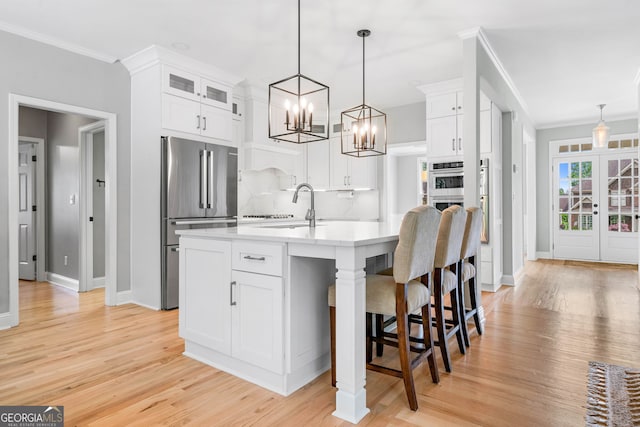 kitchen featuring decorative backsplash, a sink, light countertops, freestanding refrigerator, and white cabinetry