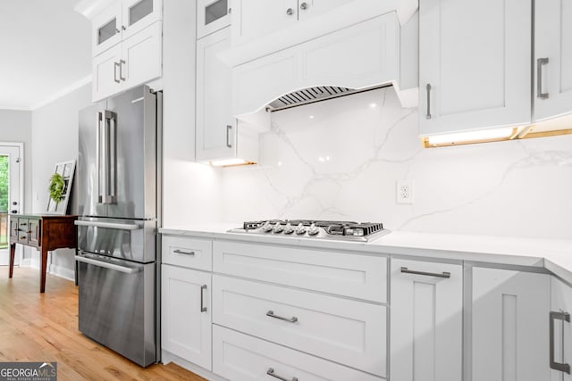 kitchen featuring ornamental molding, glass insert cabinets, white cabinetry, appliances with stainless steel finishes, and backsplash