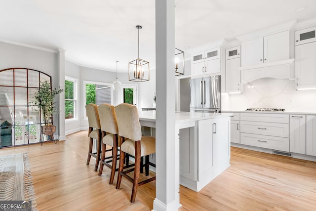 kitchen with light wood-type flooring, appliances with stainless steel finishes, white cabinets, and a center island