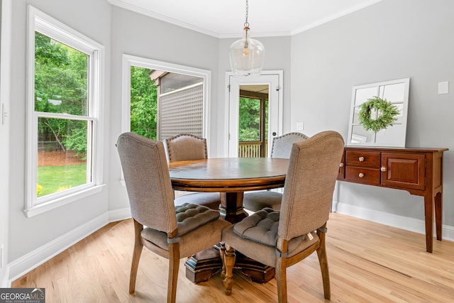 dining area with baseboards, ornamental molding, a healthy amount of sunlight, and light wood finished floors