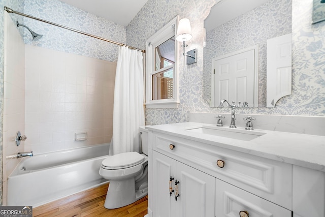 bathroom with wood finished floors, shower / tub combo, vanity, toilet, and wallpapered walls