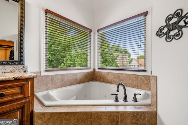 full bathroom with a tub with jets and vanity
