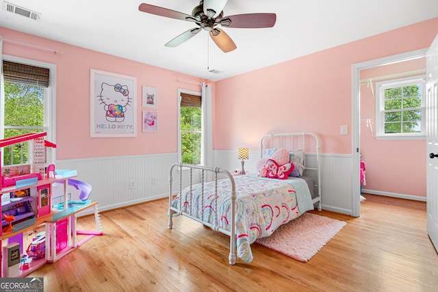 bedroom featuring wainscoting, wood finished floors, and visible vents