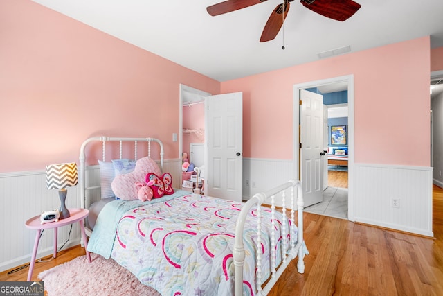 bedroom featuring visible vents, wainscoting, and wood finished floors