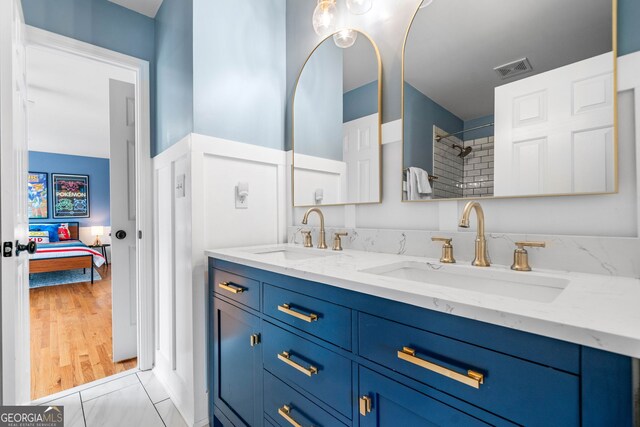 ensuite bathroom featuring a sink, ensuite bathroom, a tile shower, and visible vents