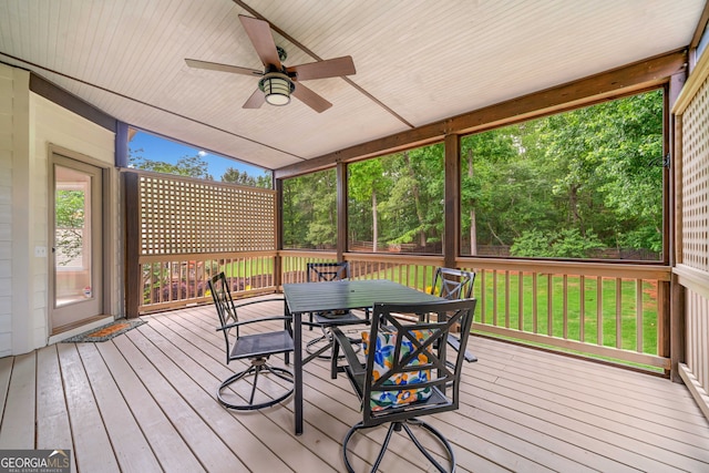 wooden terrace featuring outdoor dining area, ceiling fan, and a yard