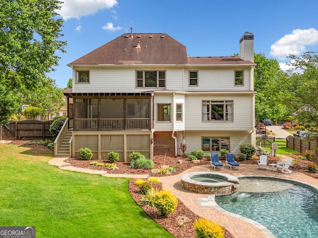 back of house featuring a fenced backyard, a yard, a chimney, and a sunroom