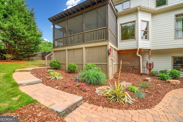 view of side of home featuring fence, stairs, and a sunroom