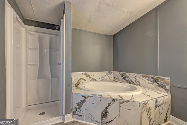 full bathroom with a textured ceiling, a garden tub, and a stall shower
