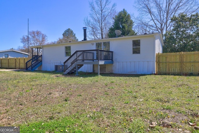 rear view of property with fence, stairs, a wooden deck, central AC unit, and a yard