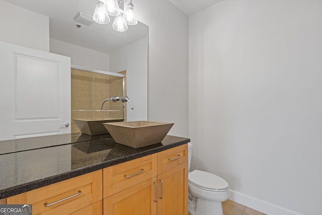 bathroom with tile patterned flooring, vanity, toilet, a chandelier, and tiled shower