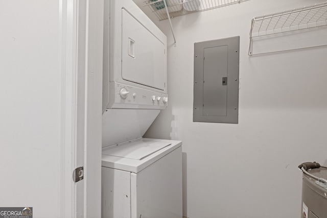 clothes washing area featuring laundry area, electric panel, water heater, and stacked washer / dryer