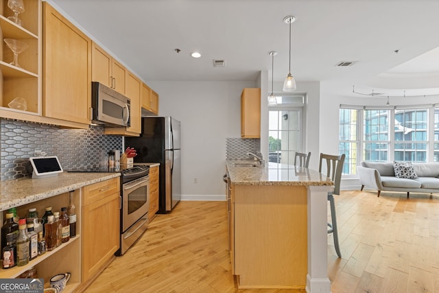 kitchen featuring a sink, light wood-style flooring, appliances with stainless steel finishes, and light brown cabinets