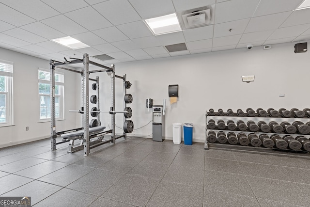 exercise room with baseboards, visible vents, and a paneled ceiling