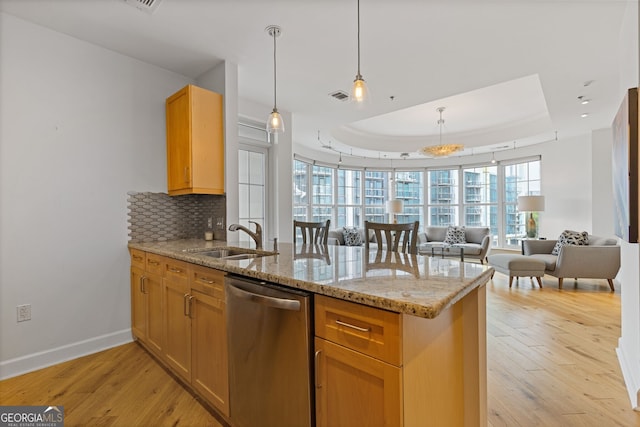 kitchen with a peninsula, open floor plan, a tray ceiling, a sink, and dishwasher