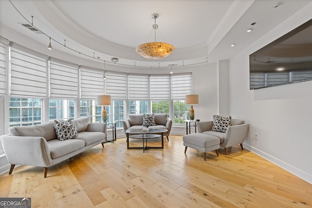 interior space with wood-type flooring, baseboards, a tray ceiling, and visible vents
