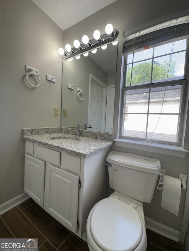 half bath featuring toilet, baseboards, wood finished floors, and vanity