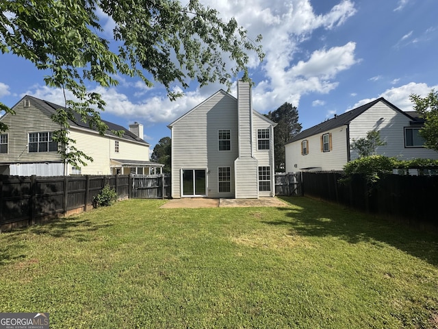 rear view of property featuring a lawn, a patio, a chimney, and a fenced backyard