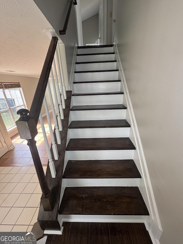 staircase featuring tile patterned flooring and a textured ceiling