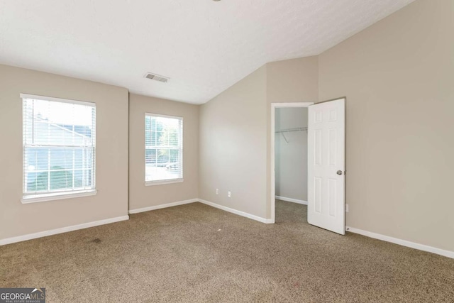 unfurnished bedroom with visible vents, carpet flooring, baseboards, and lofted ceiling