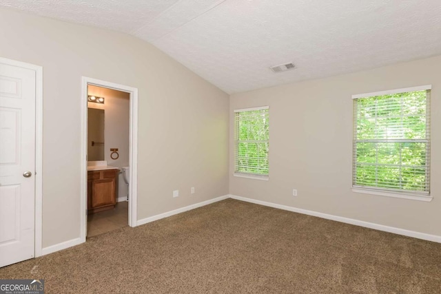 unfurnished bedroom featuring carpet floors, baseboards, visible vents, and vaulted ceiling