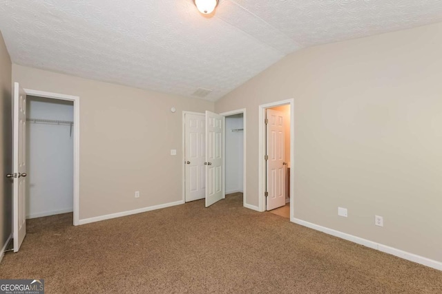 unfurnished bedroom featuring baseboards, a textured ceiling, carpet, and vaulted ceiling