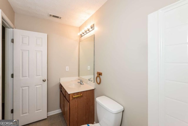 half bath featuring vanity, toilet, and visible vents