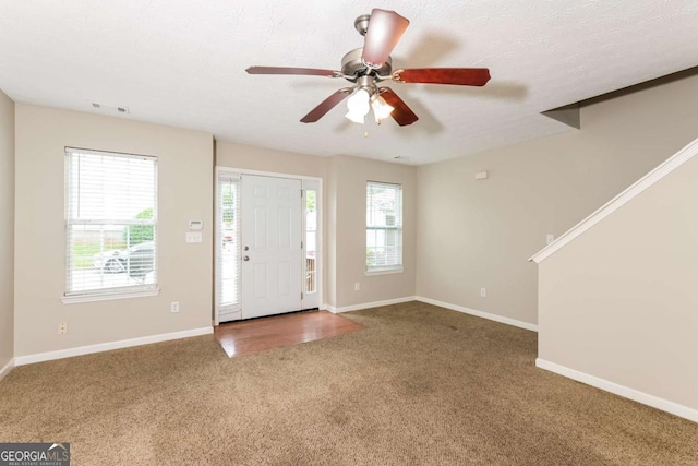 foyer featuring a ceiling fan, baseboards, visible vents, and carpet