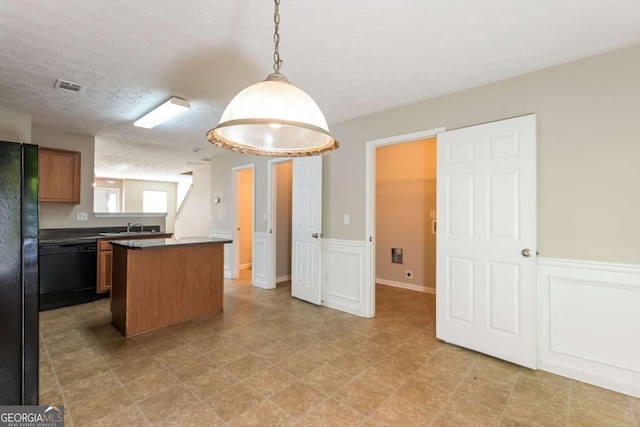kitchen with visible vents, a kitchen island, dark countertops, a sink, and black appliances